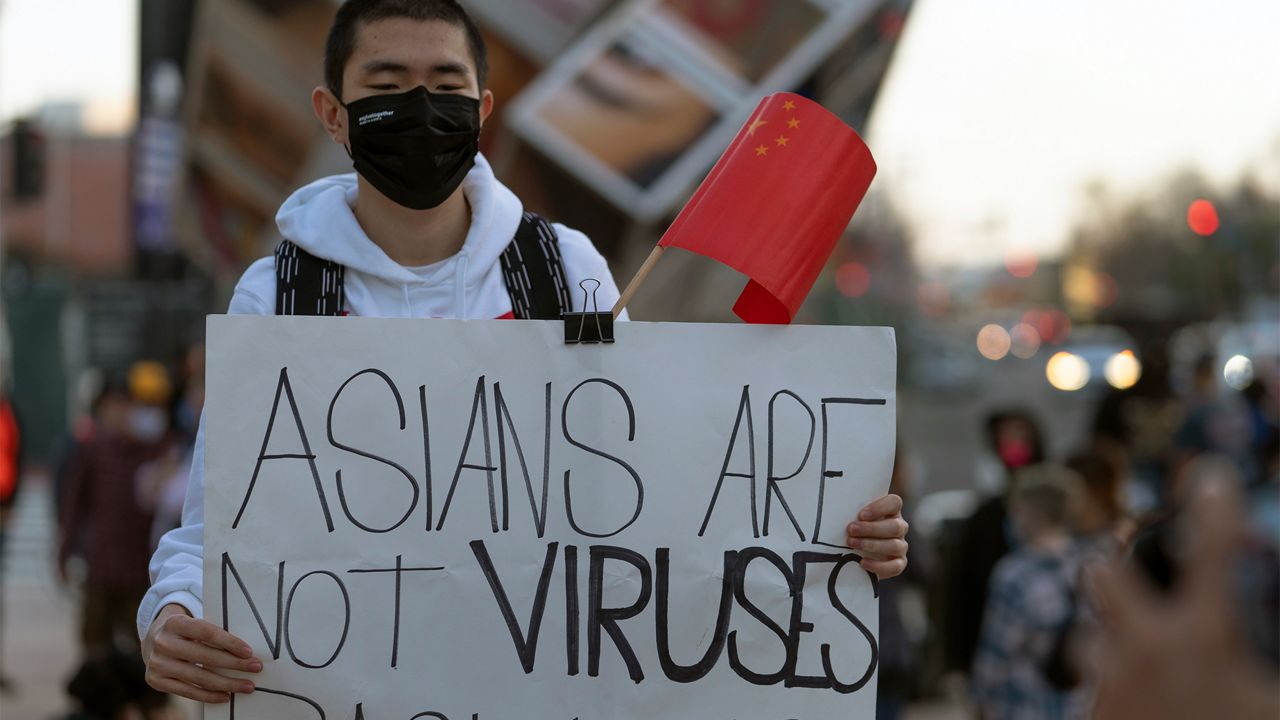 person holding up asians are not viruses sign